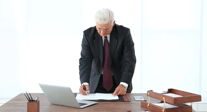 man signing documents on his desk